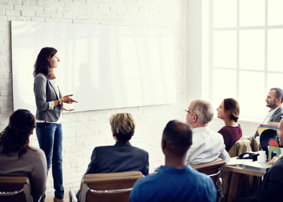 Training manager stands at whiteboard in group session.