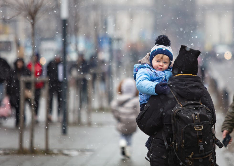 Woman carrying child to Lviv train station on snowy day