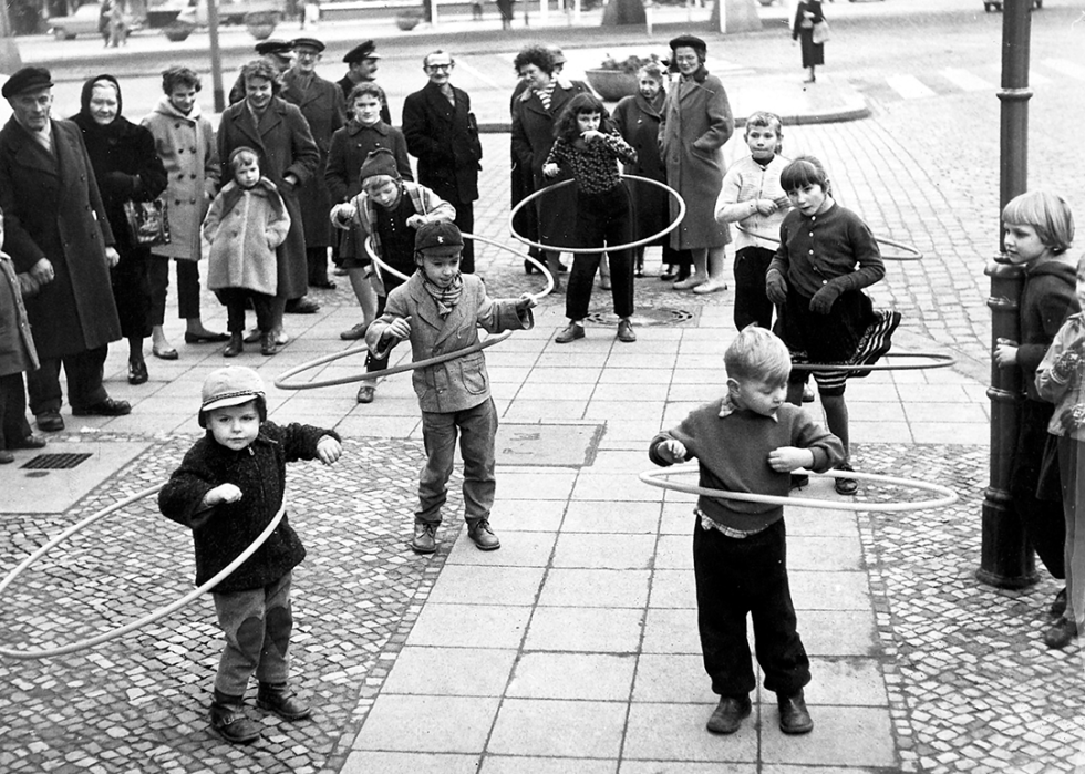 Children play with Hula-Hoops in a city street.
