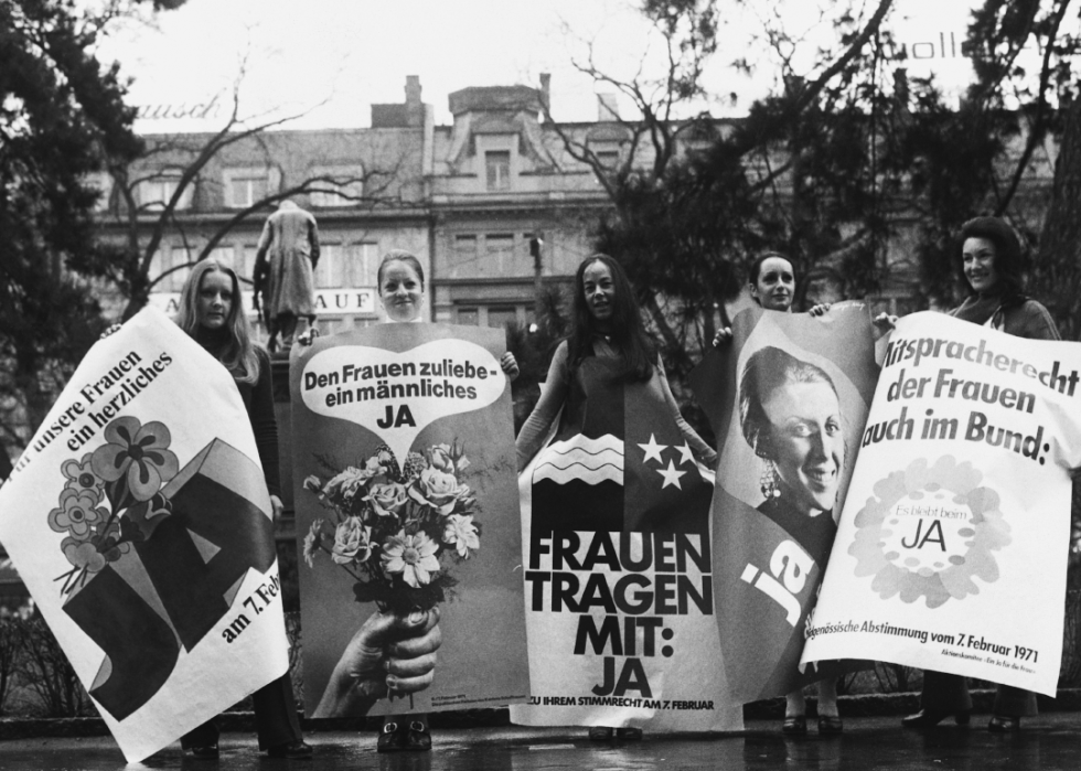 Women stand with posters before the landmark February 1971 election