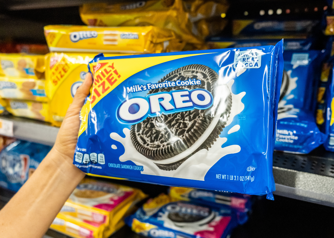 Hand holding package of Oreo cookies in supermarket.