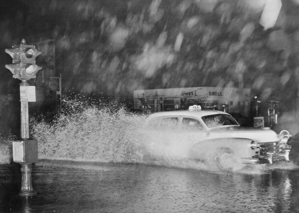 A taxi drives through flood waters during a storm.