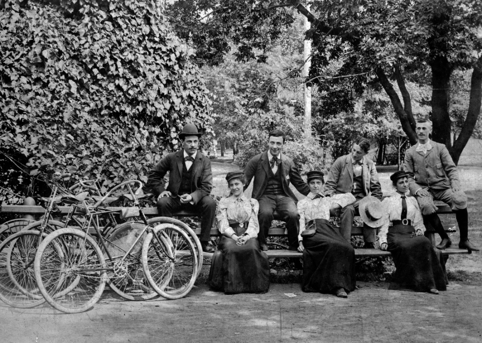 Men and women sitting with bicycles in park.