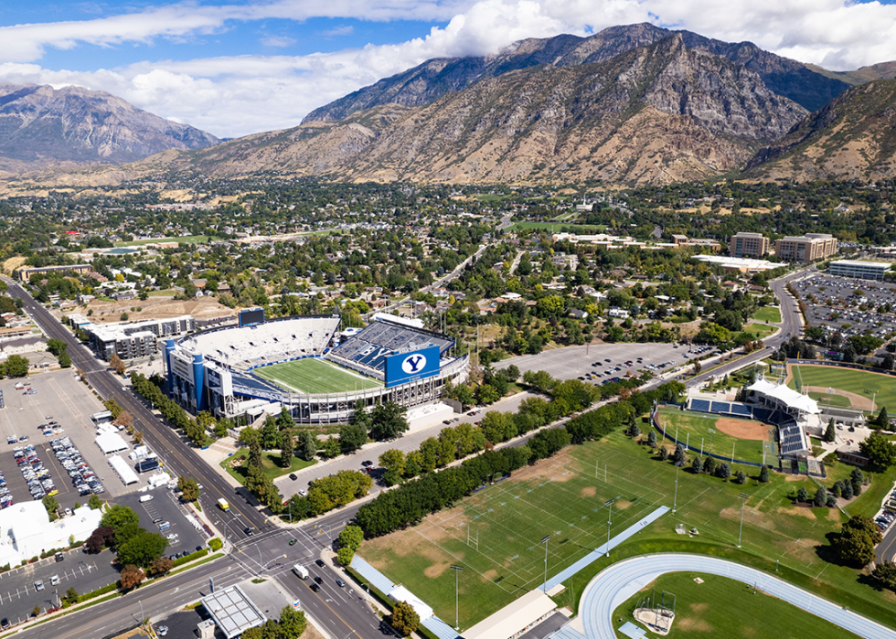Aerial view of Brigham Young University stadium and campus at the base of Wasatch Range of rocky mountains.