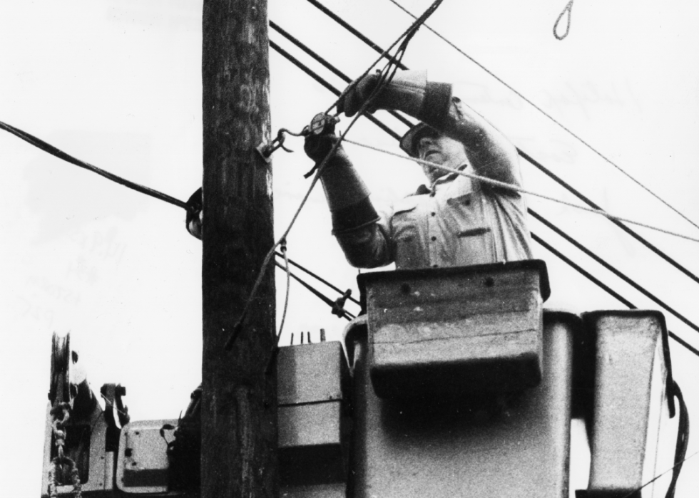 A worker in a lift bucket fixes power lines.