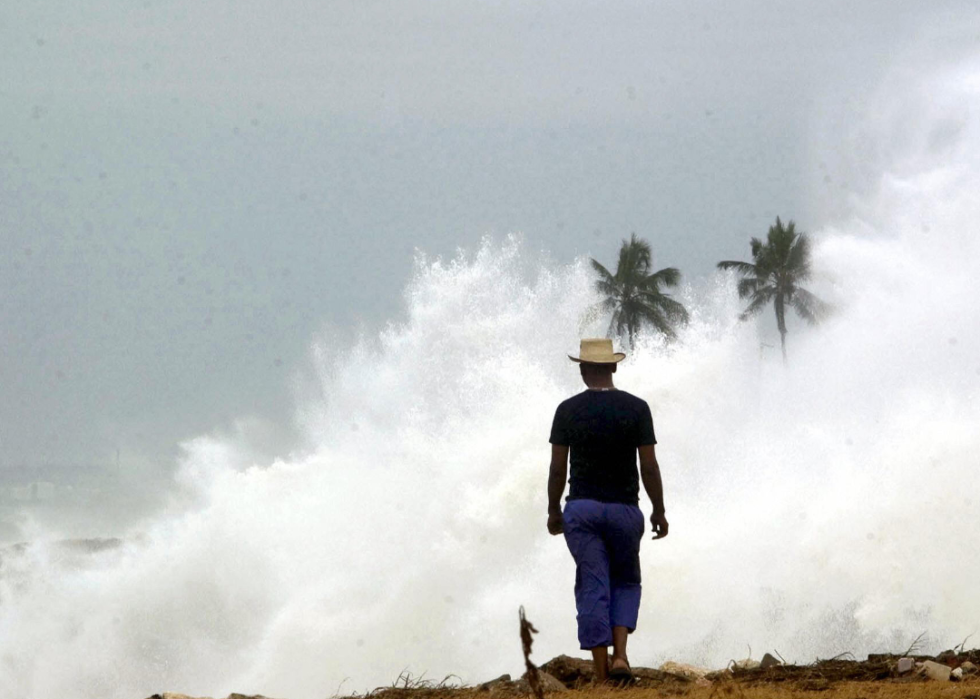 A man looks out over the large cloud of ocean spray from the sea.