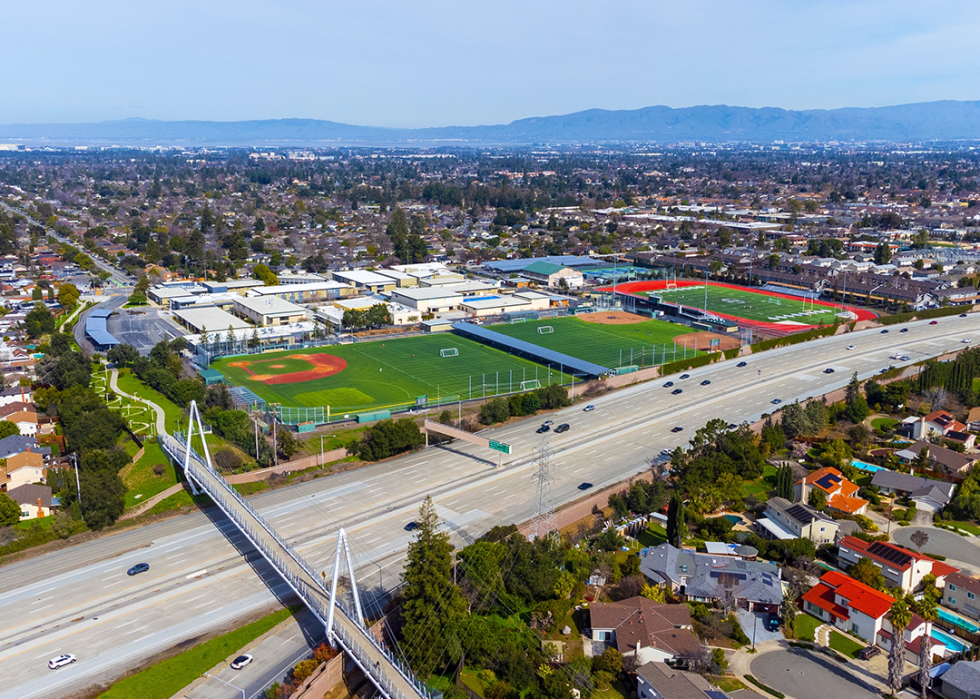 Aerial view of a high school in residential neighborhood and bicycle bridge over I-280.