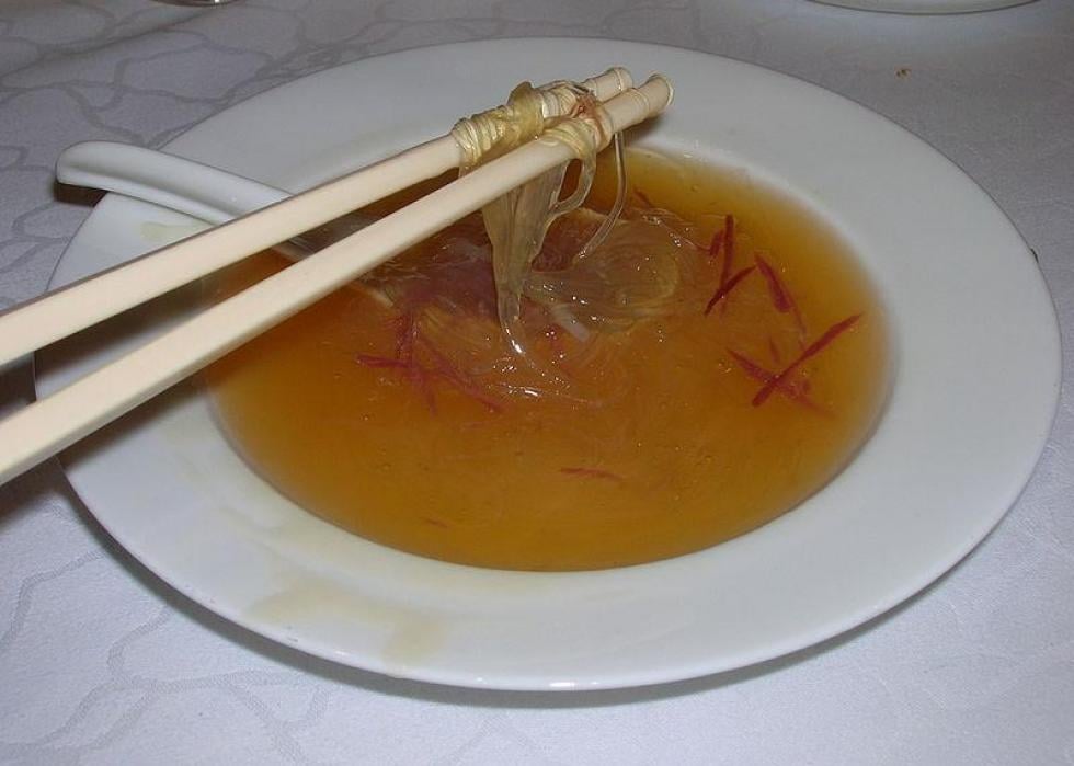 Close-up of a person eating bird's nest soup at a table.