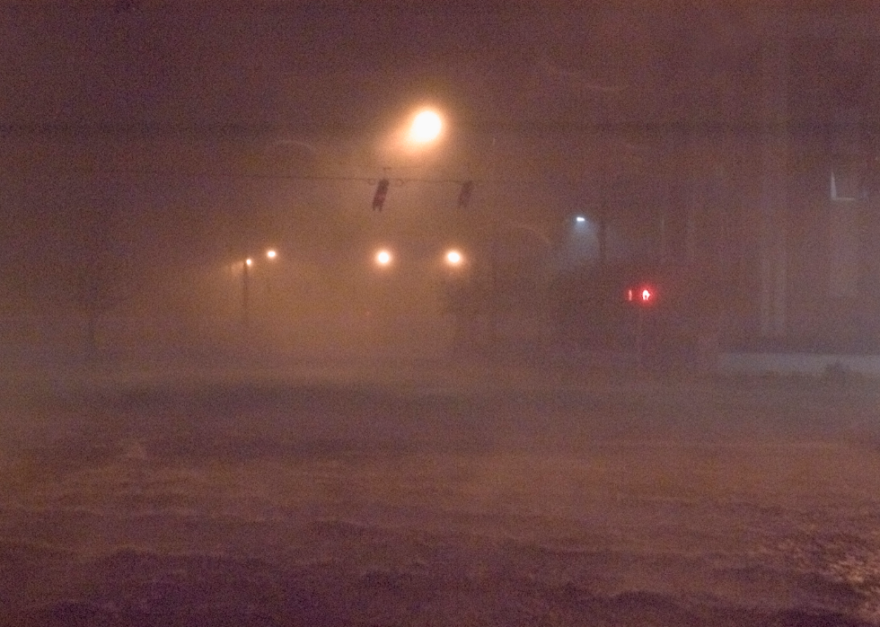 A flooded street near an intersection during a storm with low visibility.