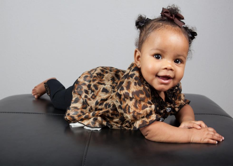 African American baby girl wearing a brown dress smiling.