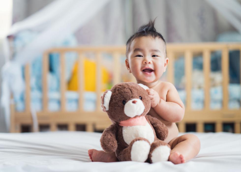 Asian baby boy holding a teddy bear.