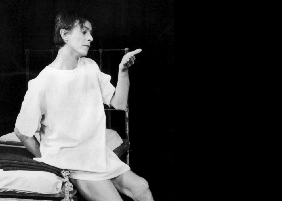 Bowie sitting on a bed on stage in The Elephant Man.