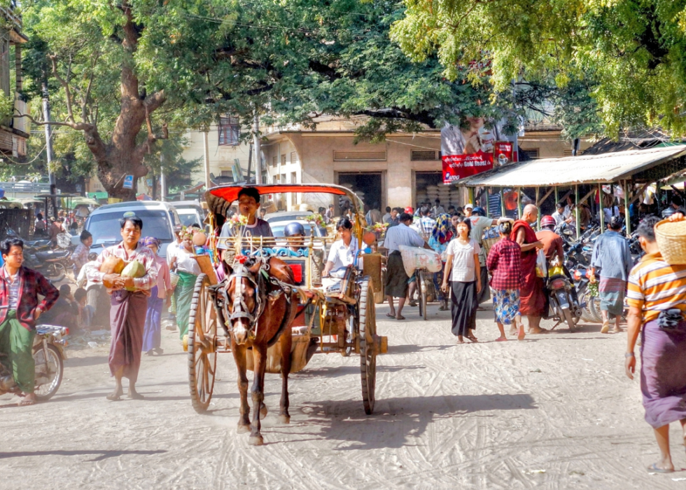 A horse-drawn taxi passes through a busy shopping area