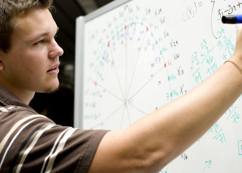 Young man at school doing a math equation.