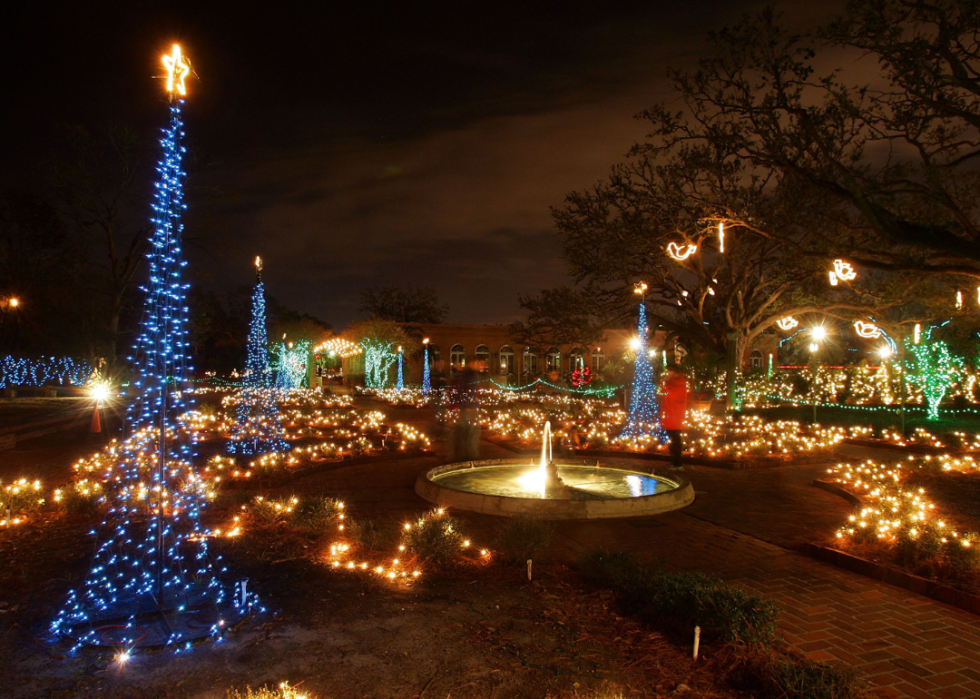 Colorful holiday lights around a park fountain.