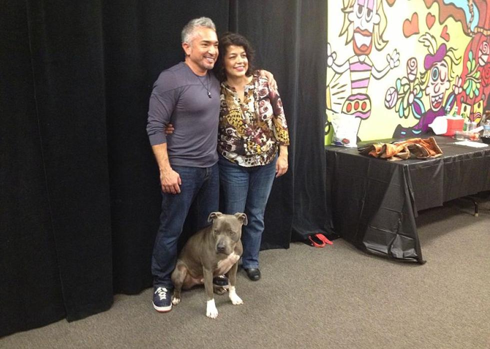Cesar Millan poses with a dog and a fan