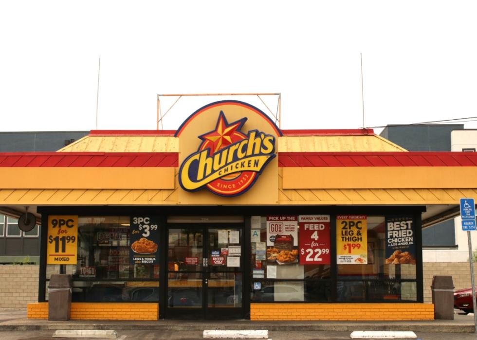 One story building with yellow bricks at the bottom, large windows, yellow and red slanted roof with the sign in the middle that says Church's chicken. 