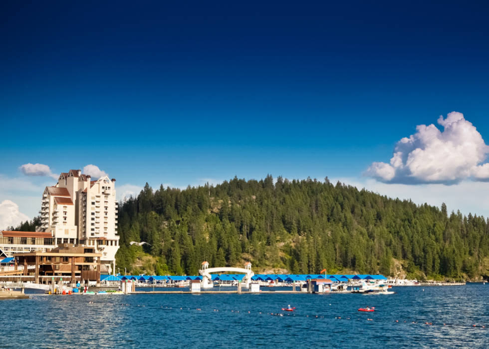 A tall white building by the lake and green mountain.