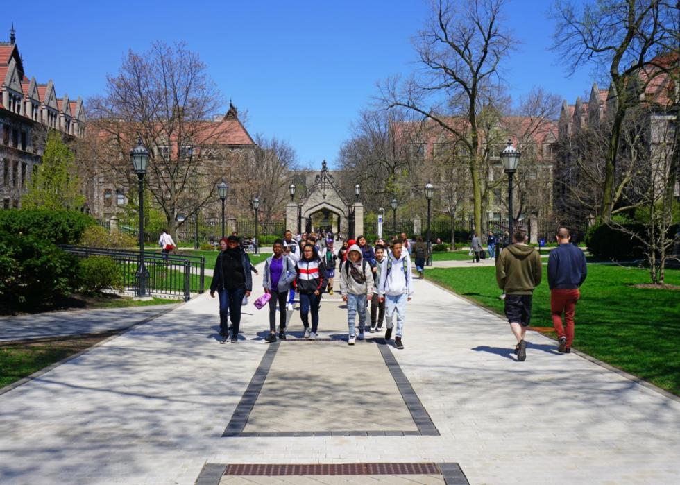 A group of college students walking with historic buildings in the background. 