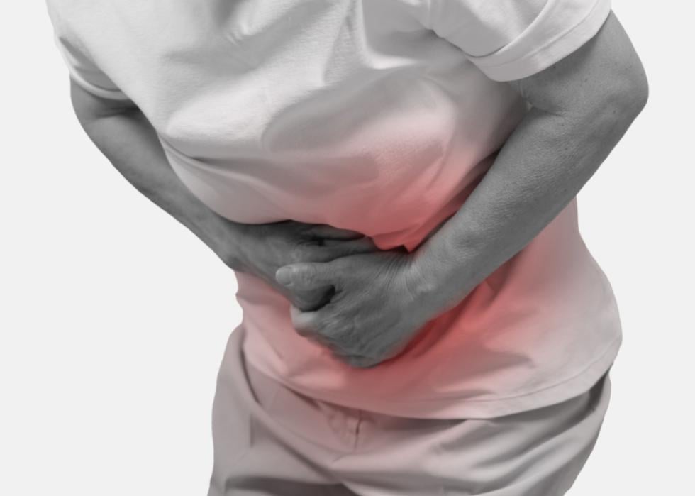 A person clutching their abdomen in discomfort or pain. The focus is on the midsection, with the person's hands tightly gripping their lower abdomen, which is highlighted with a red glow.