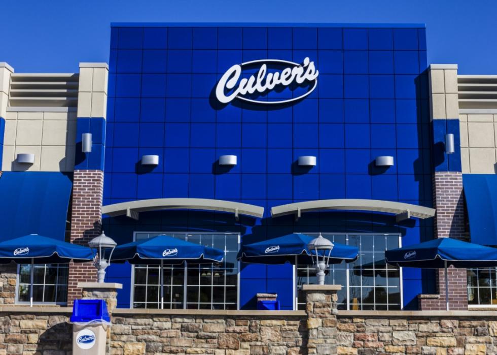 The blue exterior of Culver's restaurant with a few blue umbrellas covering tables outside.