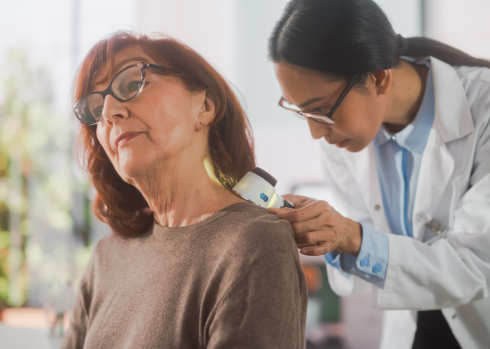 A dermatologist checking a woman's back.