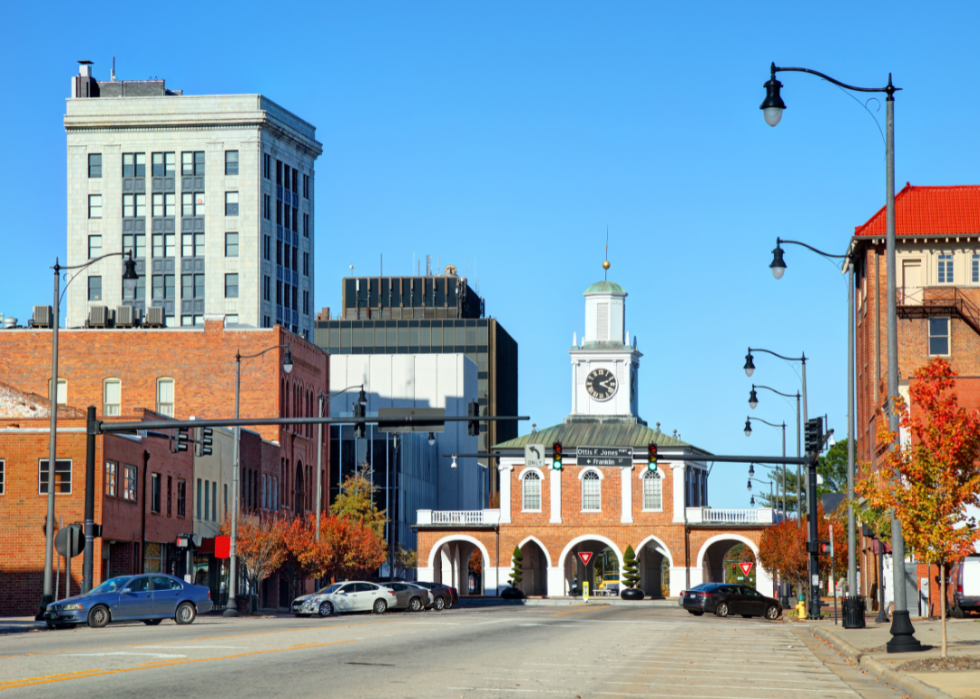 Red brick buildings along the street with a tall white building in the background. 