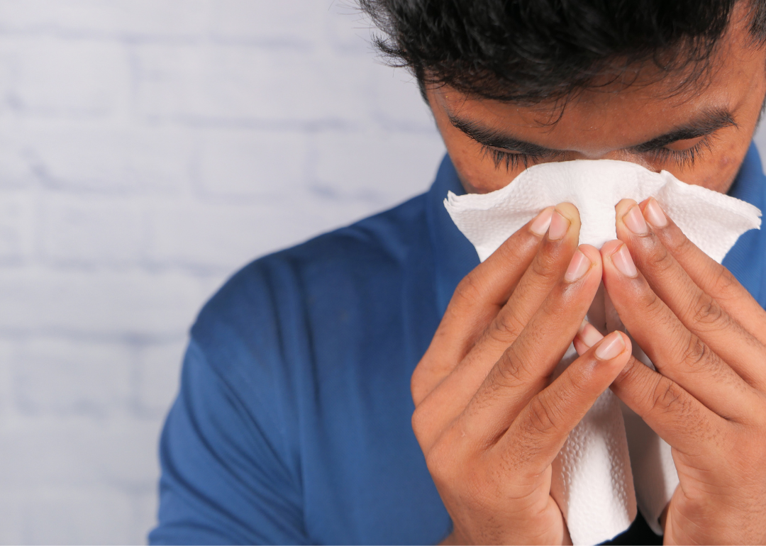 A man blows his nose in a tissue