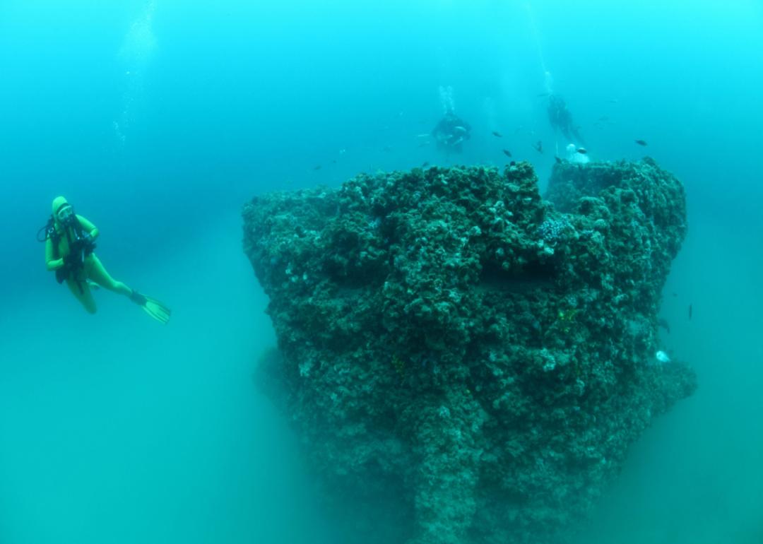 Shipwreck of the Torpedo boat Giuseppe Dezza and scuba divers underwater in the Mediterranean Sea.