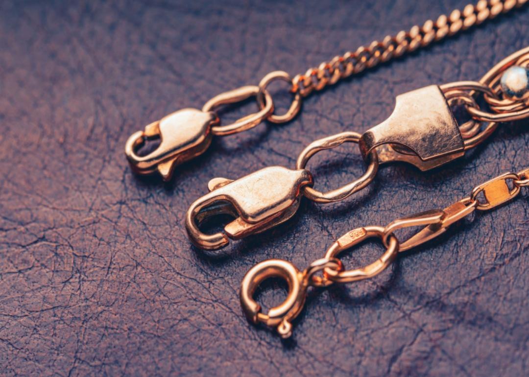 Gold clasps of a golden chains lying on a leather background.