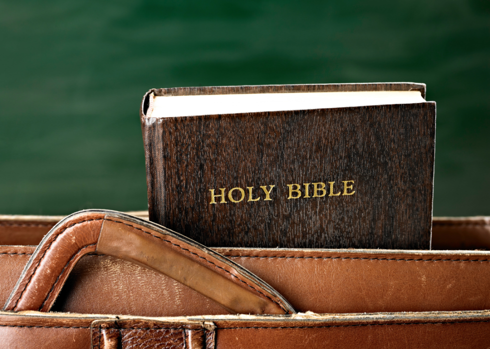 A brown briefcase with a black holy bible sitting on top of it.