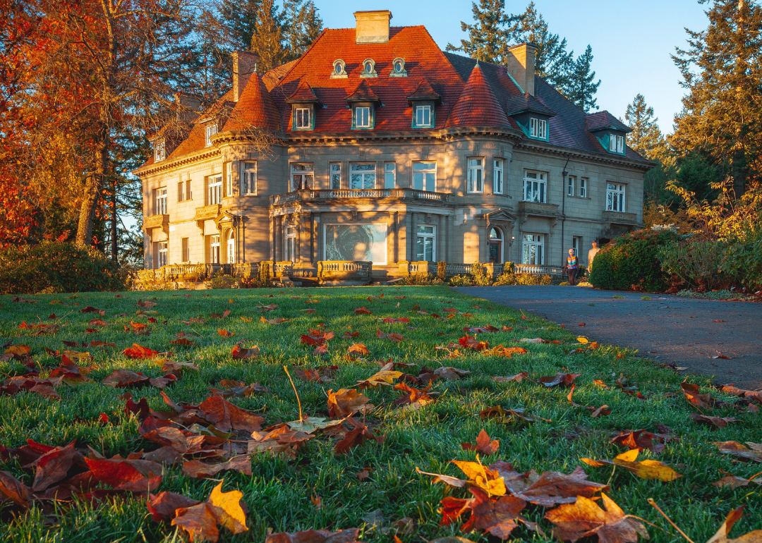 Fall leaves on the lawn in front of a mansion.