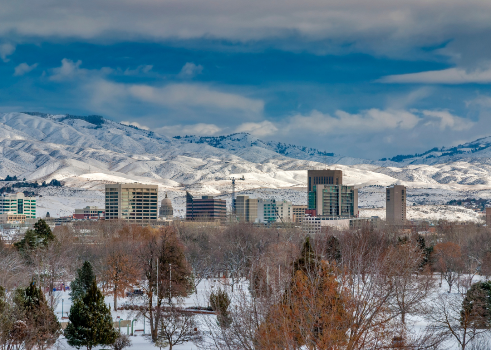 A city in winter with tall snowy mountains in the background. 