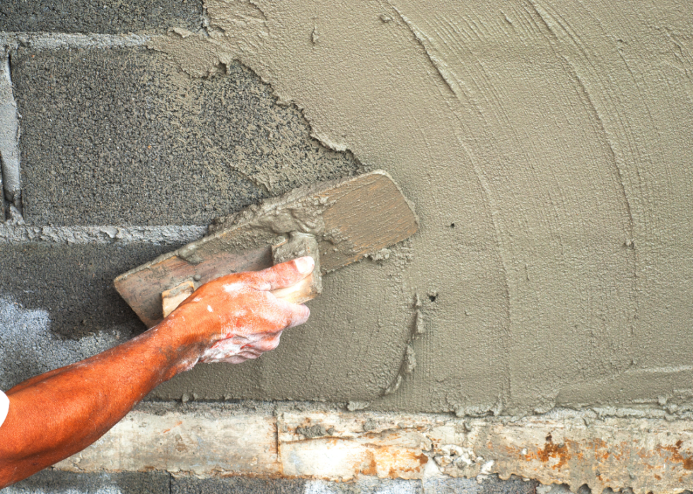 A person spreading mortar on stone.