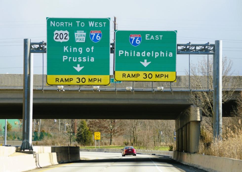 A highway overpass with two sets of green road signs.