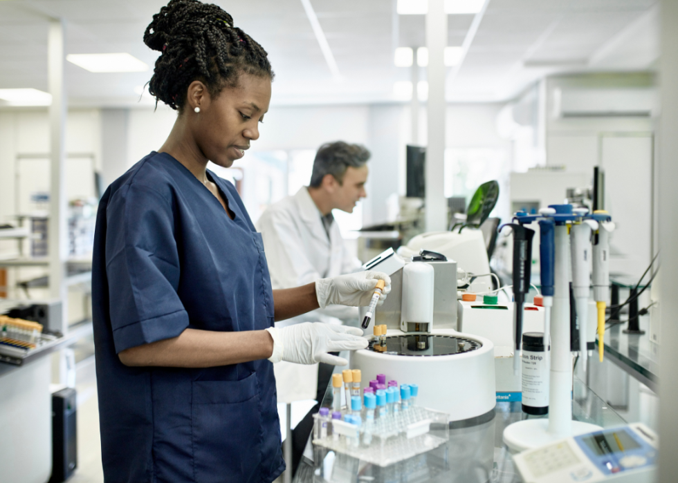 An African American female holding a blood sample in a lab.  