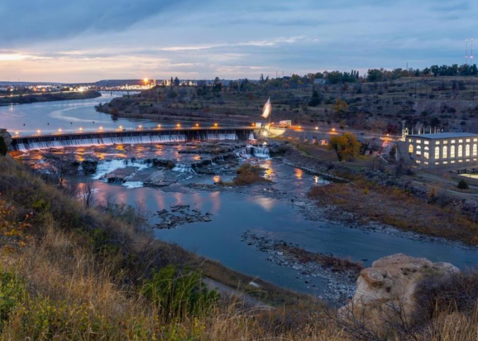 Dam and its surroundings at night with wide river reflecting the lights.