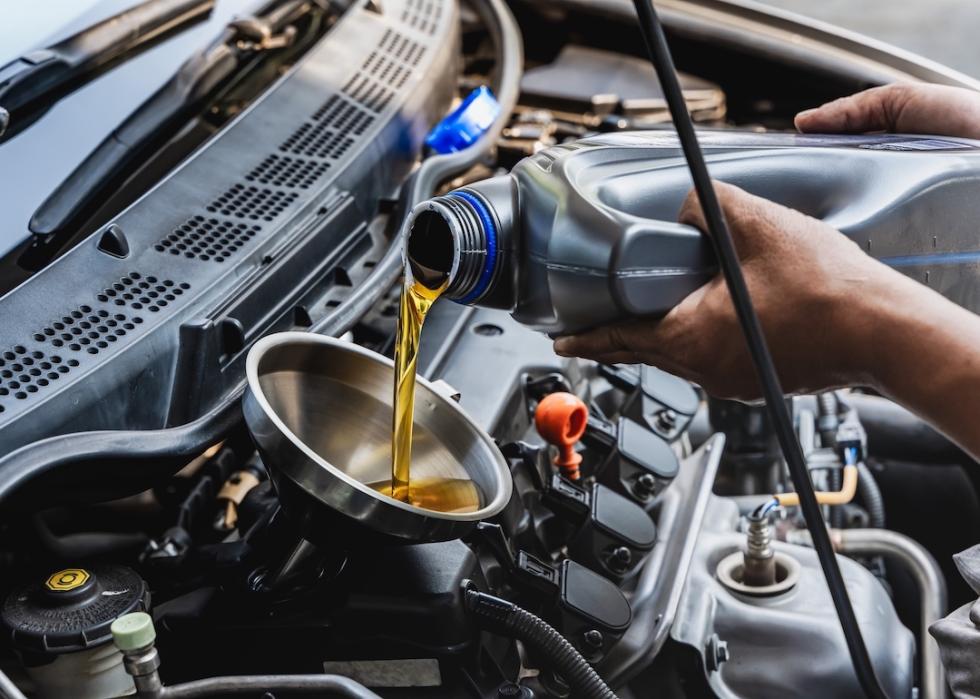 Automotive service attendant pouring engine oil into a vehicle.