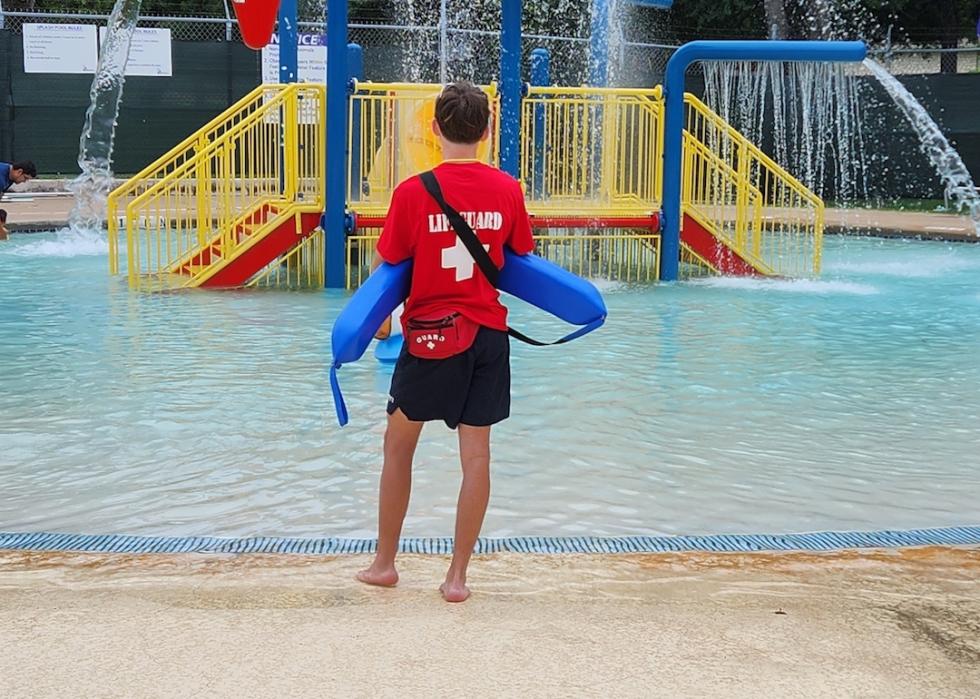 A lifeguard watching over a children's pool and splash pad.