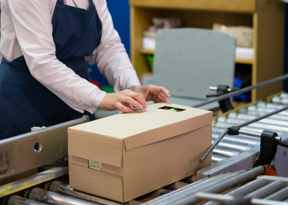 The hands of a packer packing the goods into the box.