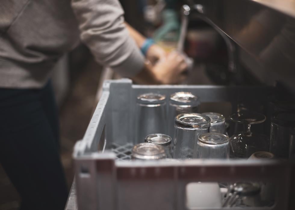 A person washing dishes in a bar.