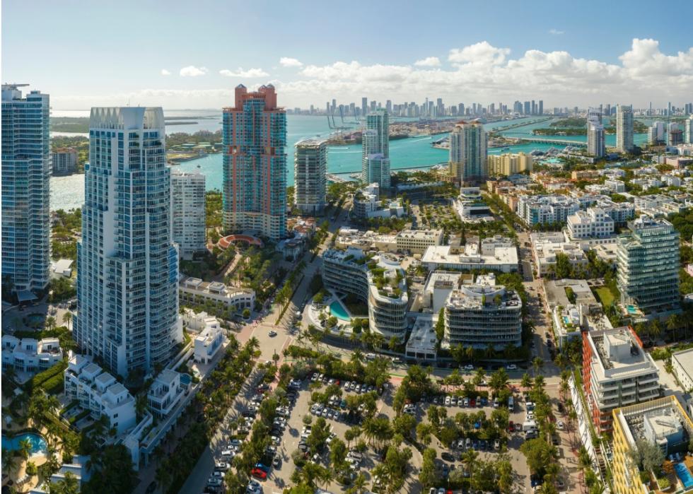 Tall, modern skyscrapers dominate the skyline. A large body of blue water stretches across the right side of the image. 