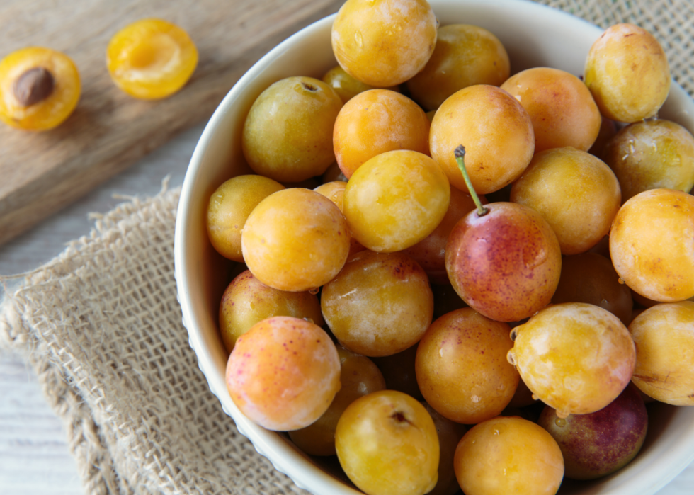 A bowl of Mirabelle plums resting on a burlap placemat.