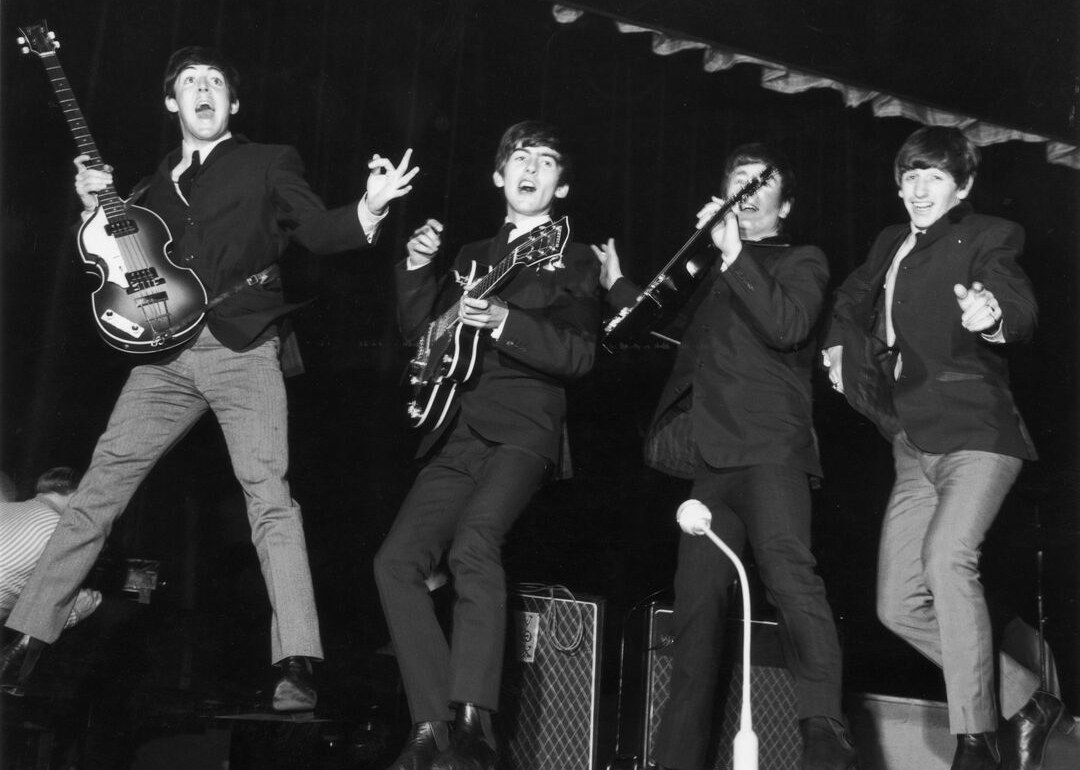 The Beatles posing for photo on stage.