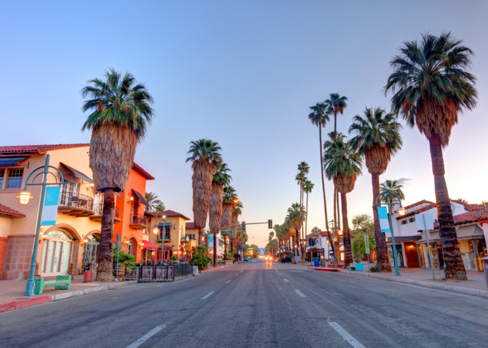 Downtown Palm Springs lined with palm trees at dusk.