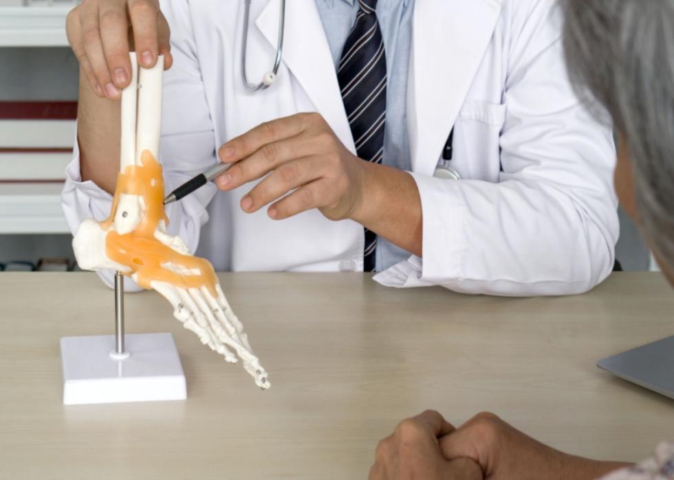 An orthopedic surgeon with a skeleton model of a foot.