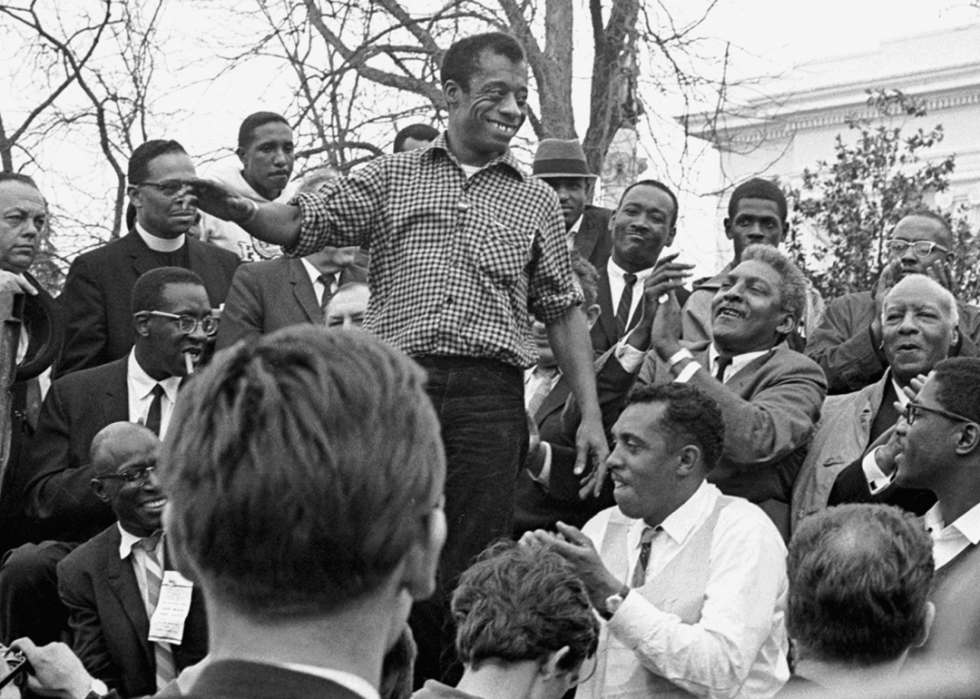 James Baldwin smiles while addressing the crowd from the speaker's platform, after participating in the march from Selma to Montgomery in support of voting rights, Alabama, March 1965.