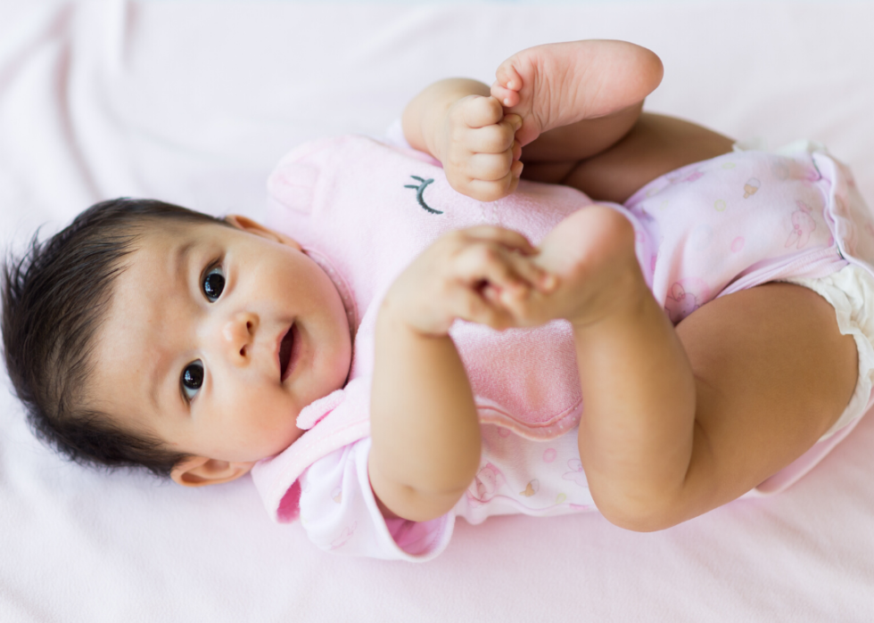 Baby girl laying on pink bedding.