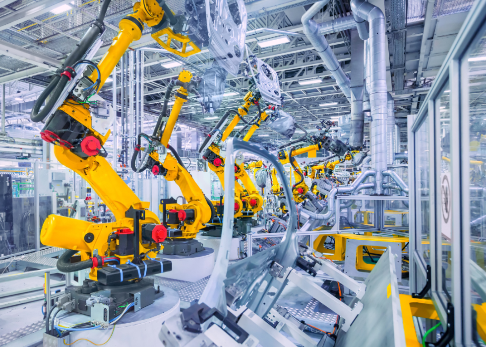 Yellow robots in a car plant assembling a part of a car. 