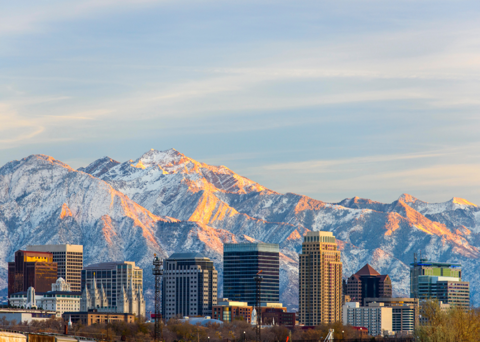 A city skyline with snowy mountain peaks in the background.